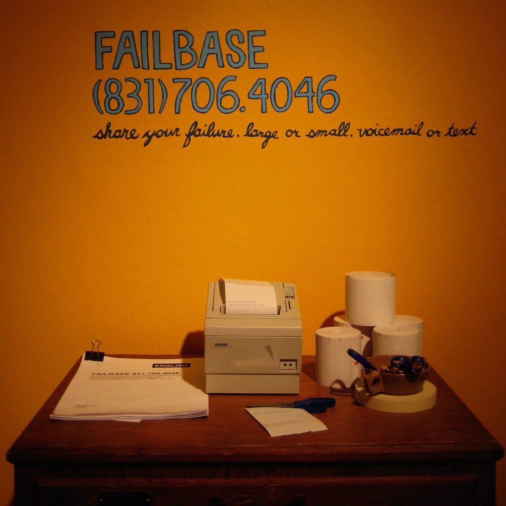 Photograph of the Failbase installation, showing a thermal printer and a wooden flat file cabinet.